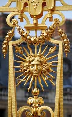 an ornate golden clock with the sun and moon on it's face, in front of