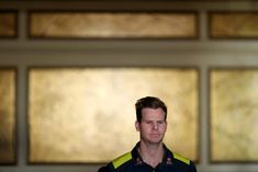 a man standing in front of a wall with gold and black paintings on it's walls