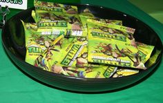 a bowl full of candy sitting on top of a green table cloth covered tablecloth