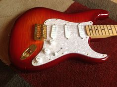 a red electric guitar sitting on top of a carpet