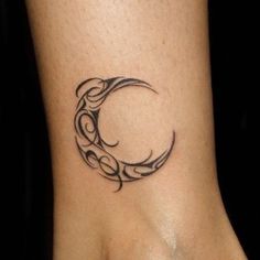 a black and white photo of a tattoo on the ankle that looks like a crescent moon