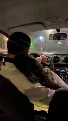 two people sitting in the driver's seat of a car with their heads up