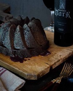 a bundt cake sitting on top of a wooden cutting board next to a bottle of wine