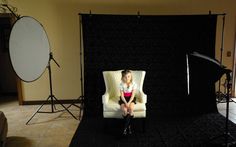 a woman sitting on a chair in front of a camera set up for a photo shoot