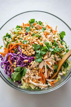 a salad with chicken, carrots, and lettuce in a glass bowl