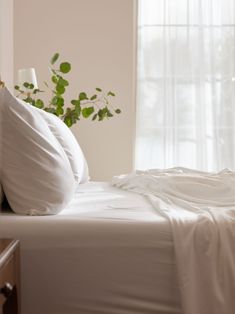 a bed with white sheets and pillows next to a window