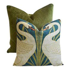 two white swans on green velvet pillows, one with gold trim and the other in blue