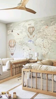 a baby's room with two cribs and a map on the wall