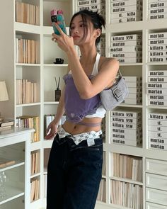 a woman taking a selfie in front of a bookshelf holding a cell phone