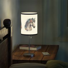 a lamp with a horse on it sitting on top of a table next to a book