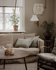 a living room filled with furniture next to a table and a potted plant on top of a window sill