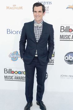 a man in a suit and tie on the red carpet at an awards event with his hands in his pockets