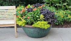 a wooden chair sitting next to a planter filled with flowers and plants in it