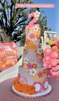 a three tiered cake sitting on top of a table next to pink and orange balloons