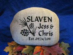 a rock with the words slayer, jesus and christ on it sitting in front of fall leaves