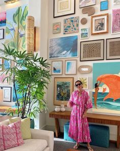 a woman standing in front of a living room filled with art