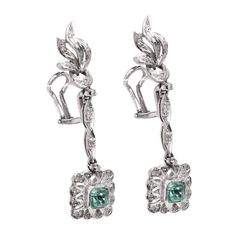 These lovely drop earrings are made of Palladium (which would date them to about the 1940s). Each has an approximate 0.60ct natural emerald at its bottom, surrounded by flourishes of palladium peppered with 42 natural diamonds (I-J color, I clarity) weighing a total of 0.20ct.The earrings have a total length of 48mm and they drop approximately 35mm from the post. Elegant Emerald Diamond Earrings In White Gold, Elegant White Gold Diamond Earrings With Emerald, Elegant White Gold Emerald Diamond Earrings, Diamond Drops, Diamond Drop Earrings, Natural Emerald, Emerald Cut, Round Brilliant, Belly Button Rings