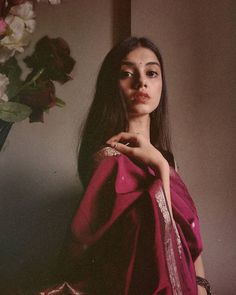 a woman in a pink dress standing next to a vase with flowers