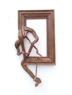 a wooden frame hanging on the side of a wall with a sculpture in front of it