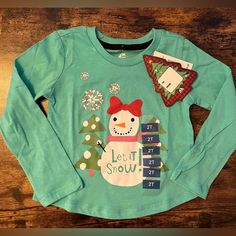 Adtn | Toddler Girls Holiday T-Shirt. Size: 2t. Color: Cockatoo- Teal Green, White, Green, Pink, Red And Orange. Long Sleeves & Crew Neck. 60% Cotton, 40% Polyester. Cute Snowman With A Red Bow On Her Head, “Let It Snow” Silkscreened On The Front. Brand New Christmas Shirt. Nwt. Msrp: $18. #Toddler #Littlegirl #Childrens #Christmas #Elf #Uglychristmas #Holidayparty #Holiday #Dressup #Costume #Xmas Toddler Elf Shirt, Girls Holiday, Red Long Sleeve Shirt, Girls Crop Tops, Childrens Christmas, Zara Shirt, Red And Orange, Tie Dye Long Sleeve, Cute Snowman