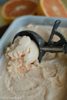 a scoop of ice cream in a bowl with orange slices around it and a metal tong