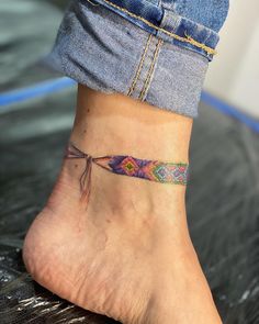 a woman's foot with a colorful tattoo on the side of her ankle,