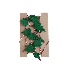 christmas decorations are wrapped in brown paper with candy canes and holly leaves on them