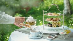 two people are serving tea and pastries to each other