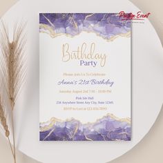 a purple and gold birthday party card on top of a white plate next to some dry grass