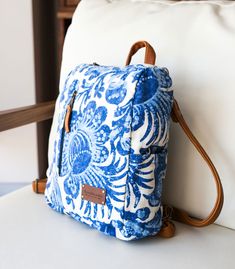 a blue and white bag sitting on top of a chair next to a pillow in a room