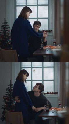 two people are sitting at a table in front of a christmas tree and one person is touching the woman's hand