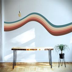 a table and two chairs in front of a wall with a wave painted on it