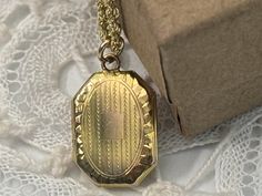 "Description: A sweet vintage 10K gold locket on a 10K gold rope chain. This locket is a rectangular shape with cut corners giving it 8 sides. The top front has an etched design of a central rectangle with etched lines on all sides. All around the outer edge is a delicate etched design that frames the locket front. This locket is quite small and a dainty, petite vintage piece on a new chain that is 16\" in length. The back of this vintage small locket has no design and has a shiny finish. The bale loop is 14K gold. The chain and the locket are hallmarked 10K. The locket is circa mid century or earlier in age.  The interior of the locket holds 2 very tiny photos and the wells are in a rectangular shape.  This petite and classic 10K gold locket opens and closes securely.  The sweet little vi Vintage Lockets, Gold Rope Chains, Gold Locket, Locket Necklace, Rope Chain, 10k Gold, Estate Jewelry, Locket, Etsy Accessories