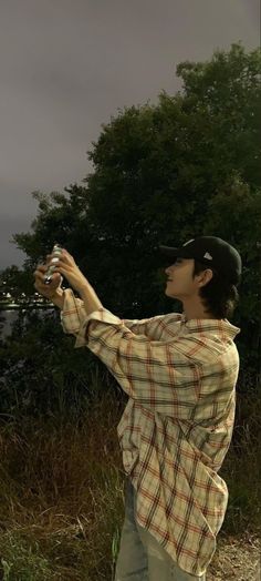 a man standing in the grass taking a photo with his cell phone