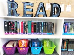 a book shelf filled with lots of books next to a sign that says read on it