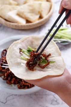 a person holding chopsticks over a tortilla