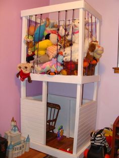 there is a doll house with many stuffed animals in the cage on top of it