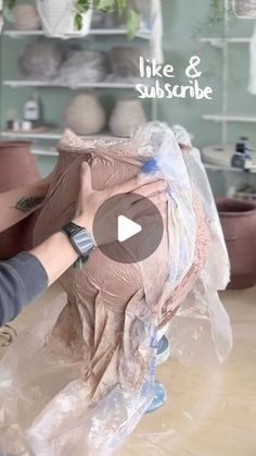 a woman is making a sculpture out of clay and wrapping it in plastic wrapper