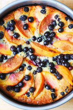 a pie with blueberries and peaches on it is sitting on a wooden table