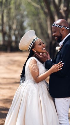 a man and woman in wedding attire standing next to each other smiling at each other