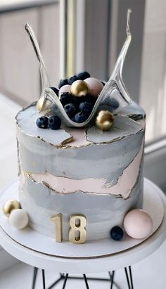 a white cake with blueberries and gold decorations