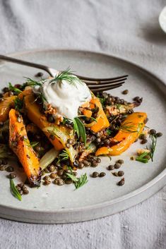 a white plate topped with carrots and lentils next to a fork on a table