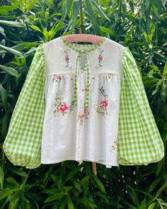 a green and white checkered shirt hanging on a clothes line with trees in the background