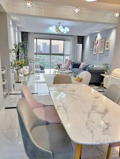 a marble dining table and chairs in a living room with large windows overlooking the city