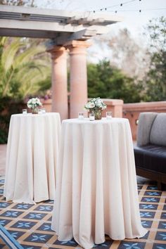 two tables with white tablecloths on them in front of an outdoor gazebo