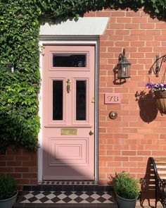 a pink front door with potted plants next to it