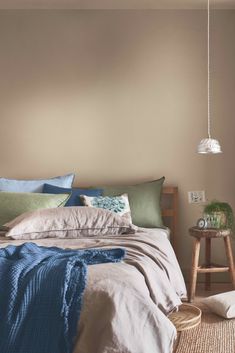 a bed with pillows and blankets on top of it next to a wooden side table