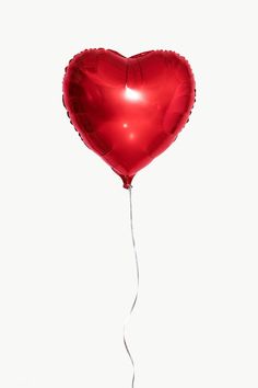 a red heart shaped balloon floating in the air