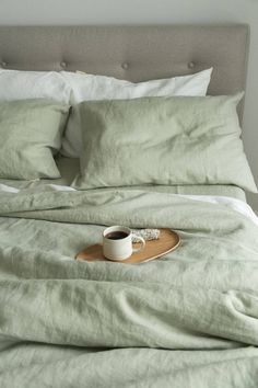 a tray with a cup of coffee on top of a bed covered in linens