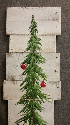 a christmas tree painted on wooden planks with ornaments hanging from the top and bottom